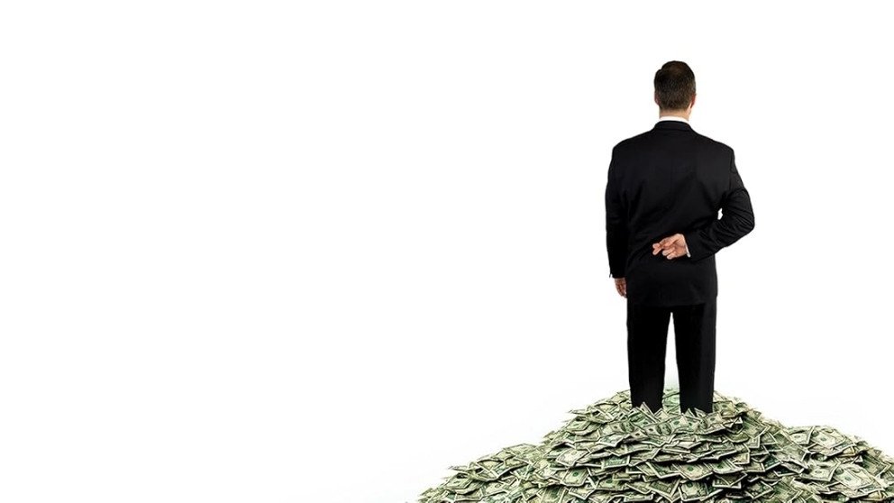 Image from Inside Job showing a man in a black suit standing on a pile of money with his fingers crossed behind his back.