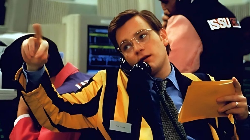Image from Rogue Trader showing Ewan McGregor as a stock trader, wearing a yellow and black jacket, on the phone and pointing.
